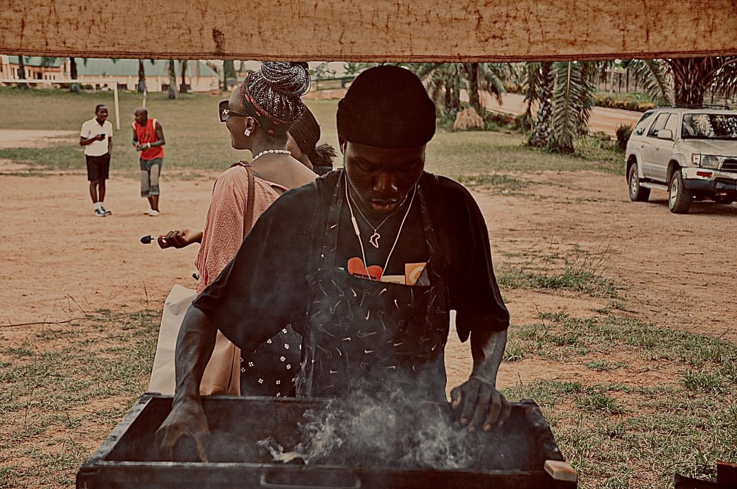 A vendor grilling food over open smoke
